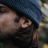 Model met muts draagt een kubusvormige oorsteker