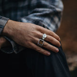 Model draagt twee zilveren ringen waarvan een zegelring en een ring met Tijgeroog