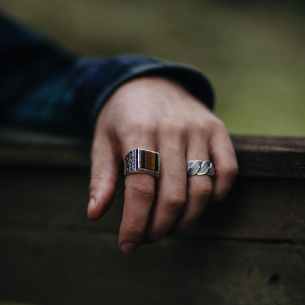 Hand met robuuste zilveren ring met Tijgeroog