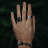 Model draagt zilveren armband met draak en twee zilveren ringen waarvan één met Mosagaat
