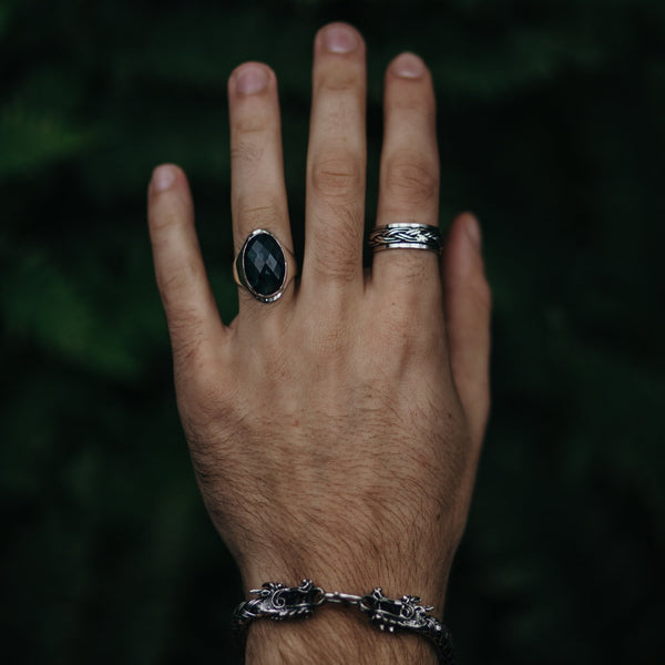 Model draagt zilveren armband met draak en twee zilveren ringen waarvan één met Mosagaat