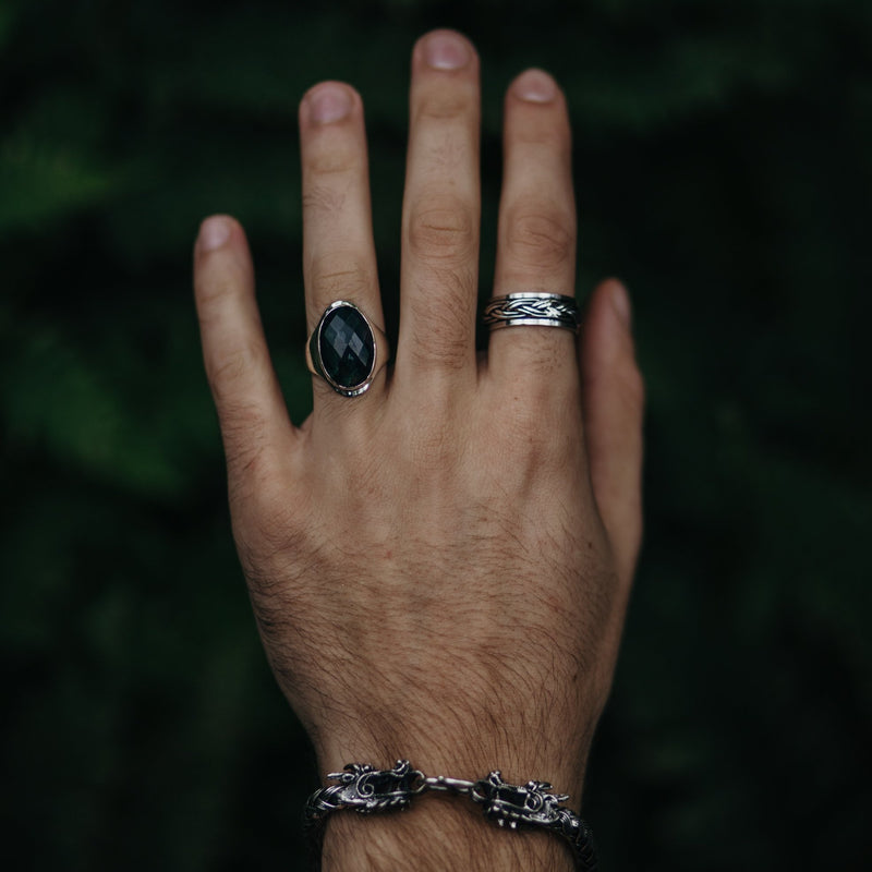 Model draagt zilveren armband met draak en twee zilveren ringen waarvan één met Mosagaat